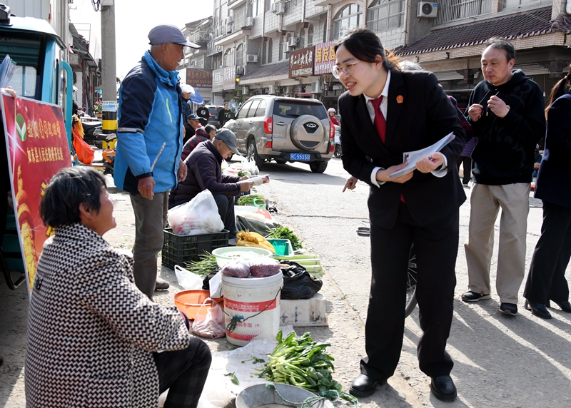 ①干警在“法律早市”向菜農發放普法宣傳折頁.jpg